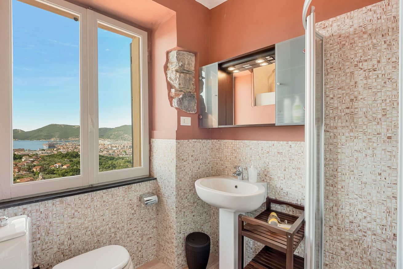 Une salle de bain avec une grande fenêtre, un lavabo et un miroir.