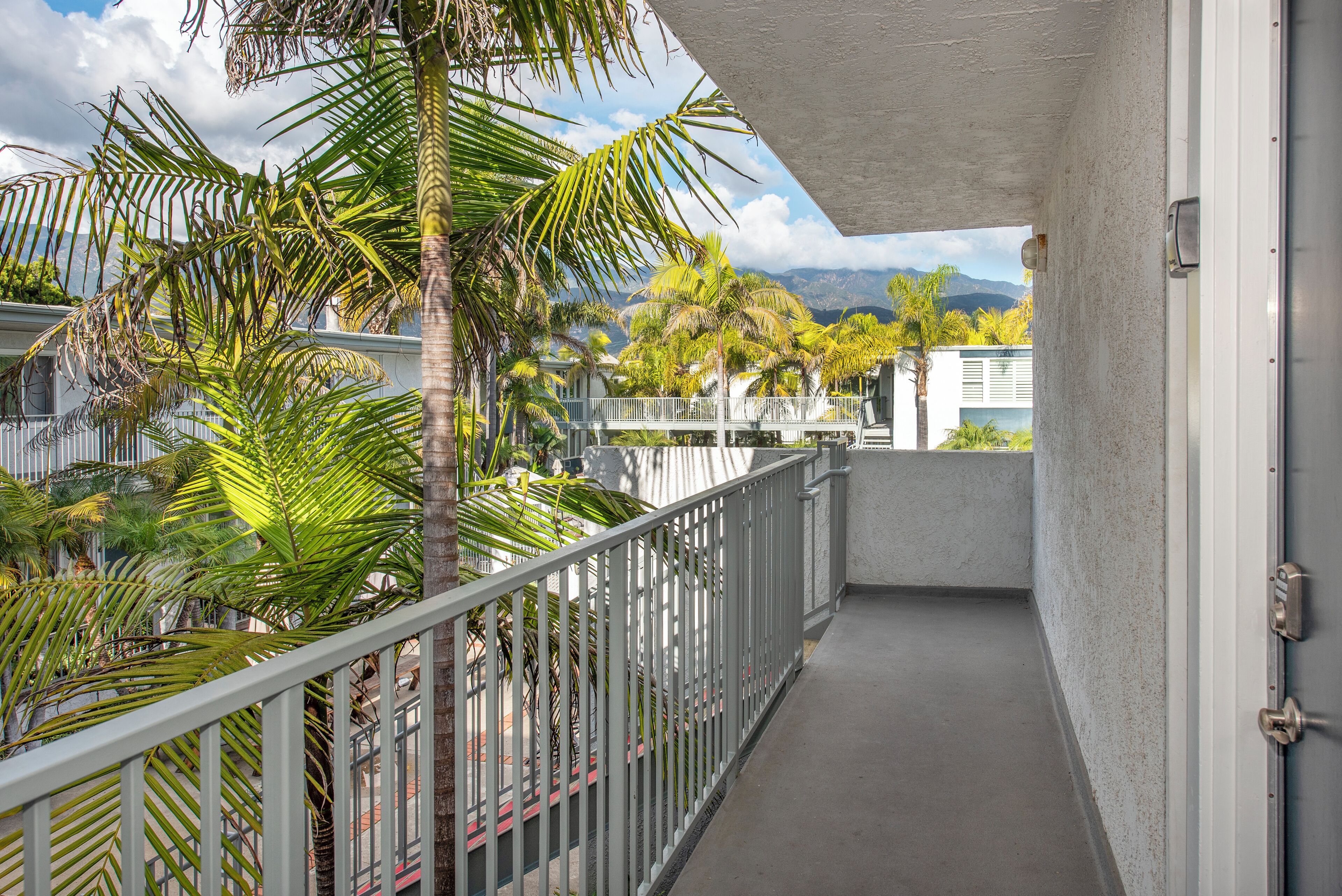 A balcony with a view of palm trees and mountains.