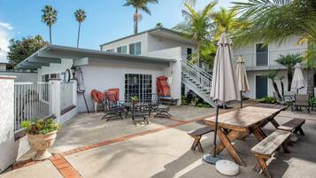 A residential patio with outdoor furniture, a staircase, and a palm tree.