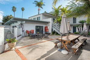 A residential patio with outdoor furniture, a staircase, and a palm tree.