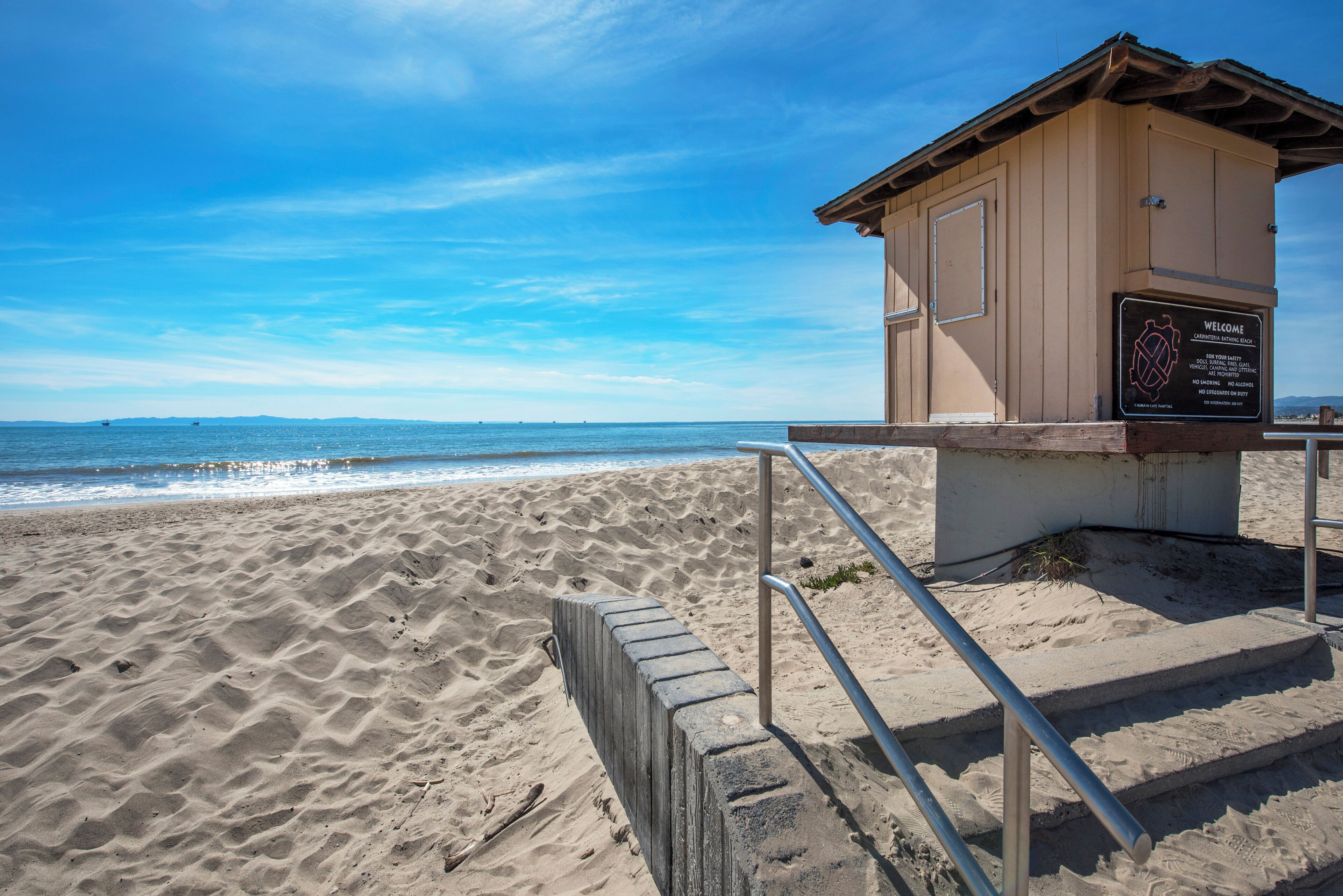 A lifeguard tower at a beach with a clear sky and calm sea.