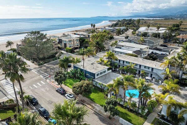 A residential area with modern buildings, a swimming pool, and a beach in the background.
