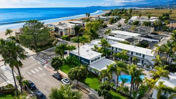 A coastal residential area with modern buildings, a visible swimming pool, and a clear view of the beach.
