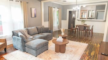 A living room with a grey sectional sofa, a coffee table, and a dining area with a table and chairs.