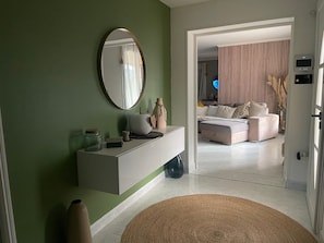 A modern living room with a white console, a round mirror, and a large window.
