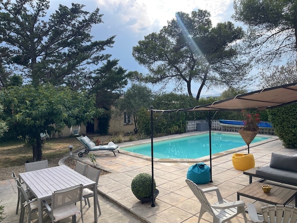 A poolside area with a pool, lounge chairs, a table, and chairs.