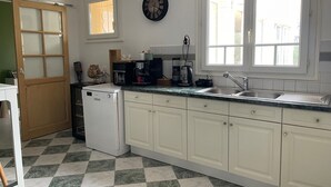 A kitchen with white cabinets, a dishwasher, a coffee maker, and a clock on the wall.