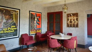 A dining area with red upholstered chairs, a round table, and posters on the wall.