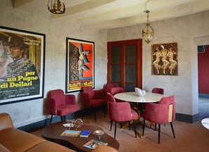 A dining area with red upholstered chairs, a round table, and posters on the wall.