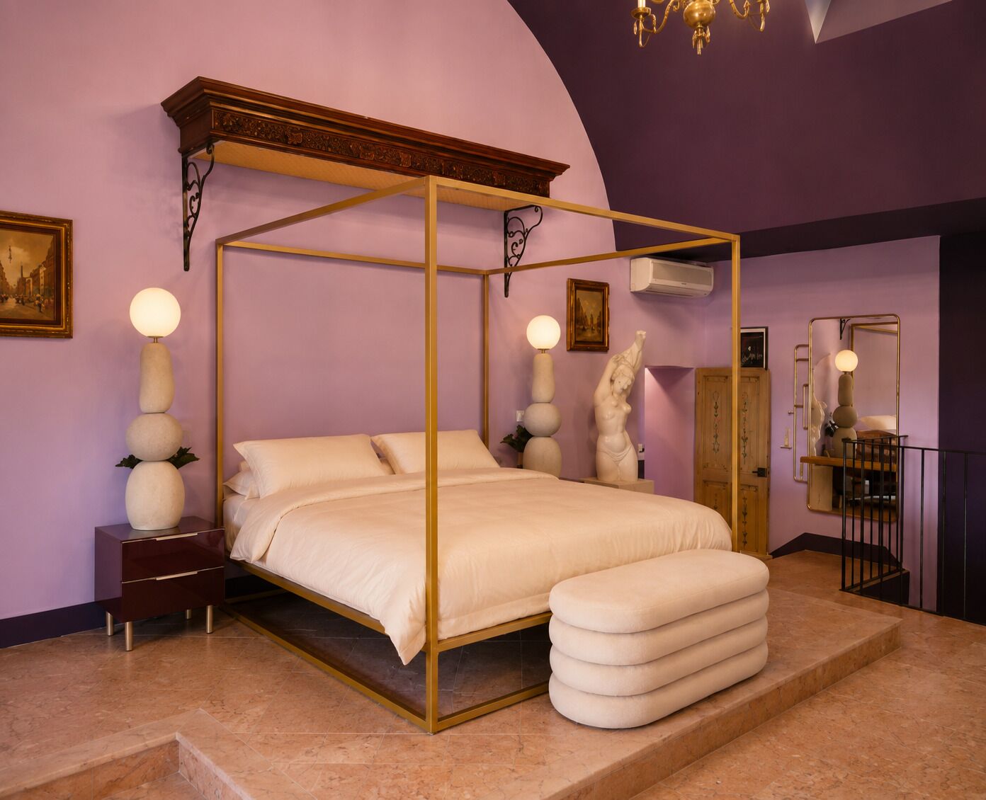 Un lit à baldaquin, une table de chevet, un miroir et une statue accrochée au mur.