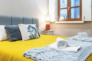 Ein Hotelzimmer mit einem Bett, Kissen, einer Nachttischlampe, einem Fenster und einem Handtuch auf dem Boden.