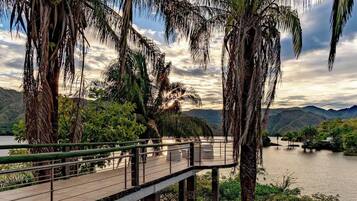 A pool area with palm trees and a view of a lake and mountains.