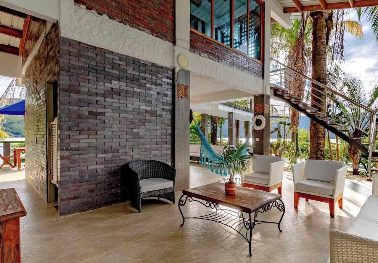 A spacious outdoor area with a brick wall, wicker furniture, a hammock, and a staircase leading to an upper level.