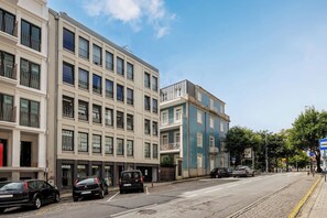 A street view with a row of parked cars, a building with multiple floors, and a clear sky. - City Center Apartment w/ Fast WiFi & Kitchen (Porto)