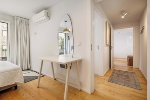 A hotel room with a bed, a desk, a mirror, and a view of the outside. - City Center Apartment w/ Fast WiFi & Kitchen (Porto)