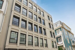 Edifício de vários andares com fachada uniforme, grandes janelas e varandas com grades de metal.