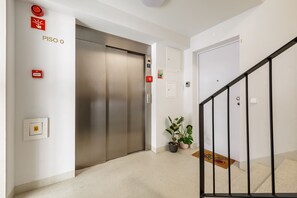 A hallway with an elevator, a staircase, and a potted plant. - City Center Apartment w/ Fast WiFi & Kitchen (Porto)