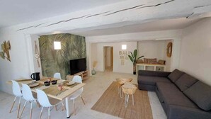 Een moderne woonkamer met een eetgedeelte, een grijze bank en een televisie.