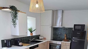 Een moderne keuken met een centraal eiland, inbouwapparatuur en een hangende lamp.