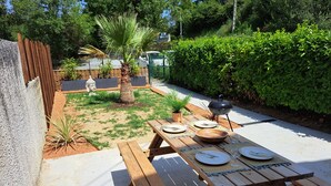 Een houten picknicktafel buiten, compleet met borden, bestek en een barbecue.