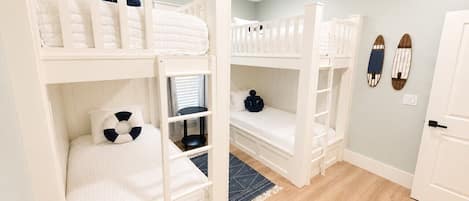 Ein Schlafsaalzimmer mit Etagenbetten, einem kleinen Tisch, einem Stuhl, einem Teppich und einer Tür.