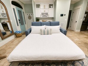 Un dormitorio con una cama grande, cabecera azul y pared blanca.