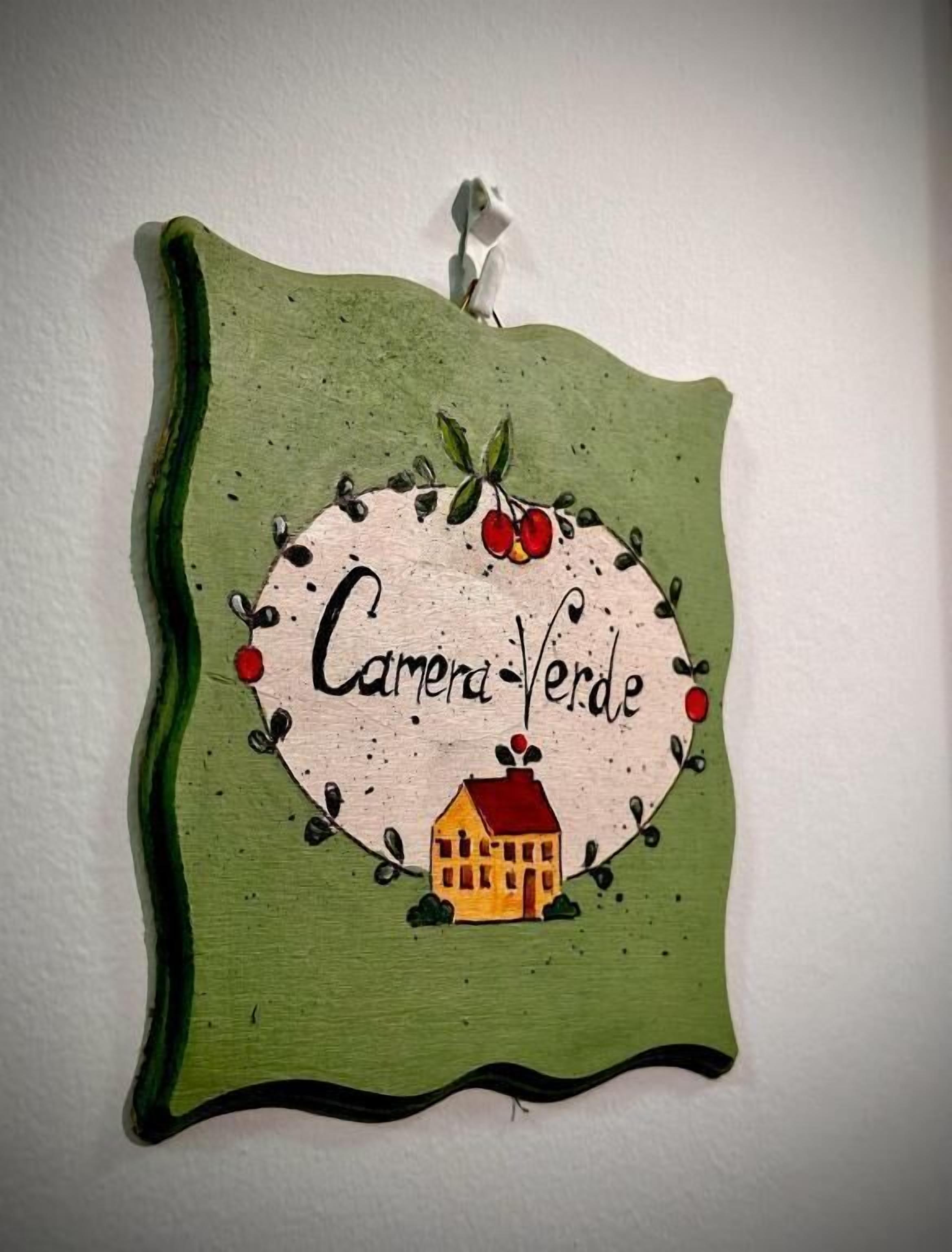 A wall-mounted decorative piece with a house illustration and the text 'Camena Verde.'