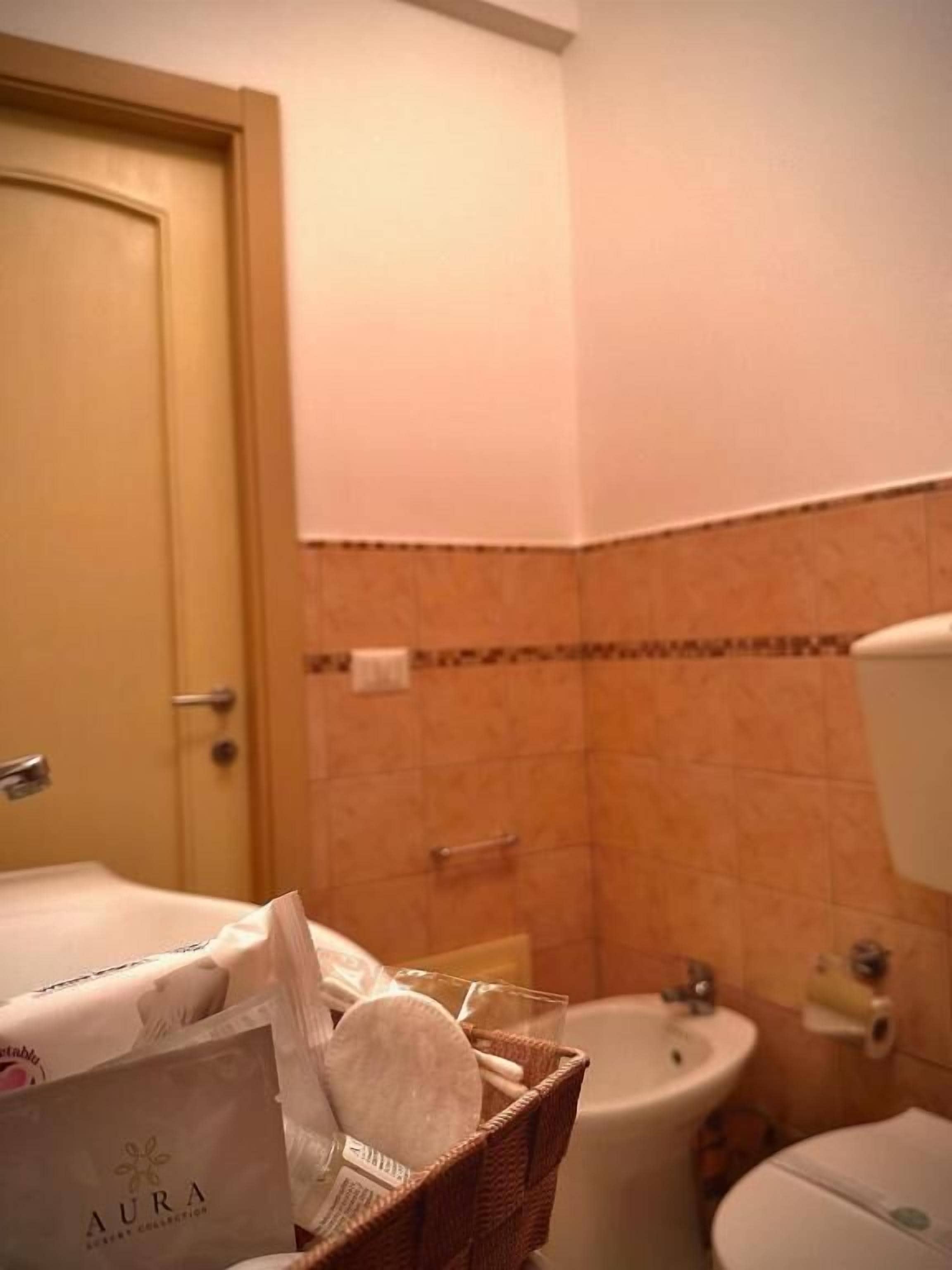A bathroom with a toilet, sink, and a basket of toiletries.
