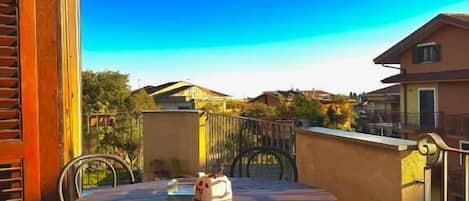 Mesa redonda con sillas en un balcón, con vista a una zona residencial.