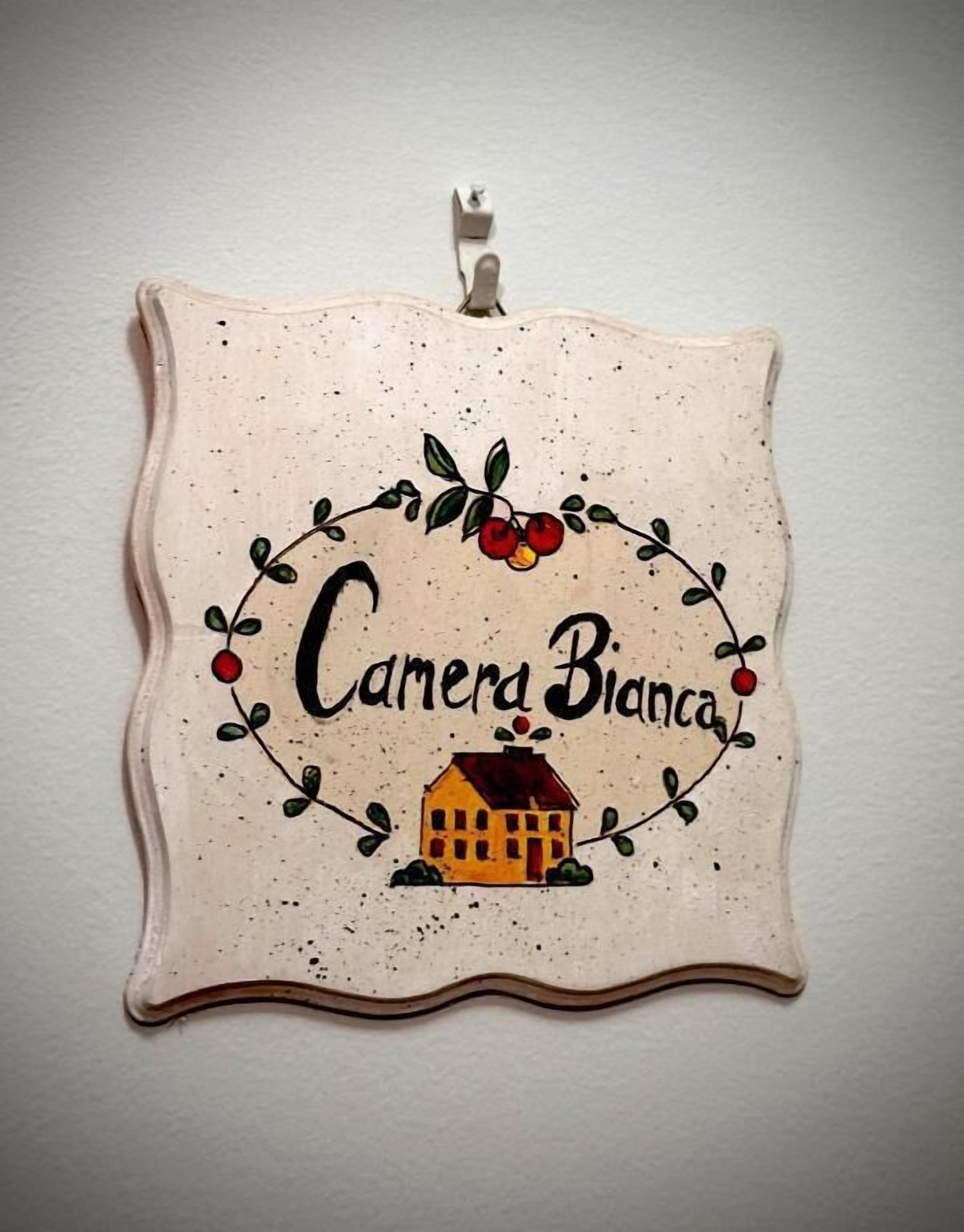 Un adorno de pared con una ilustración de una casa y el texto 'Camera Bianca'.