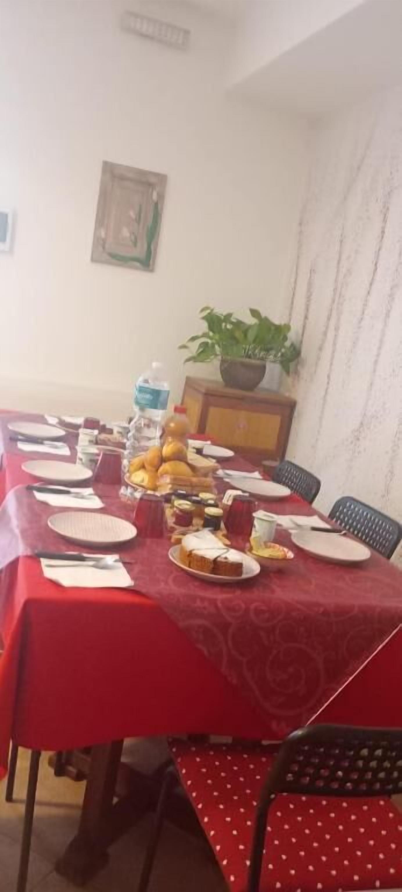 A dining table set with plates, cups, and food, surrounded by chairs.
