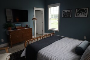Une chambre à coucher avec un lit, une commode et un téléviseur fixé au mur.