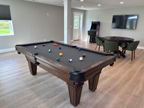 A pool table with balls, a television, and a dining area with chairs. - NEW—The Sandee Gables Cottage at Indian Lake (Lakeview)