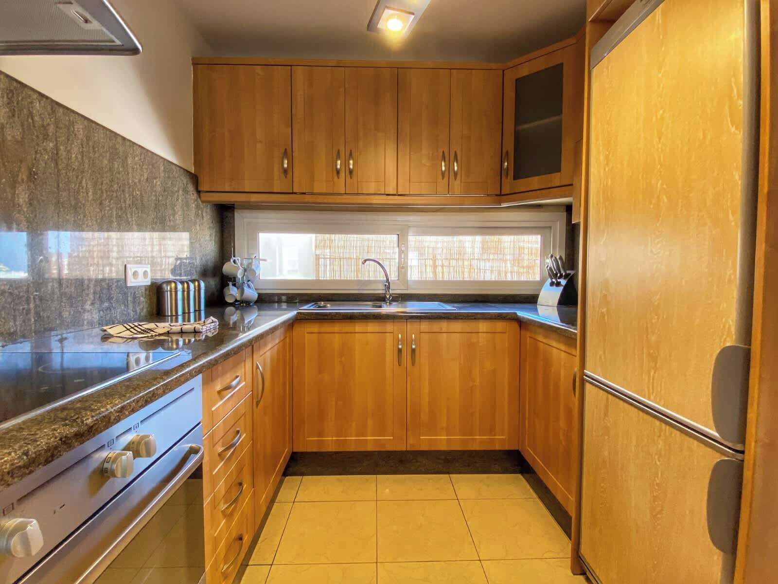 A kitchen with wooden cabinets, a stainless steel sink, and a built-in oven.