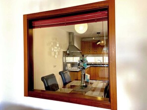 A dining area with a table, chairs, and a view into the kitchen through a window. - Los Corales 1 - Four Bed Townhouse (Arona)