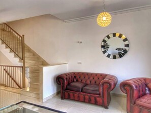 Ein Wohnzimmer mit Treppe, einem runden Spiegel und zwei Ledersofas.