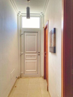 A hallway with a white door, a pendant light, and a wooden door on the right. - Los Corales 1 - Four Bed Townhouse (Arona)