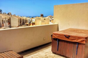 A rooftop terrace with a wooden bench, a storage unit, and a view of the cityscape and sea. - Los Corales 1 - Four Bed Townhouse (Arona)