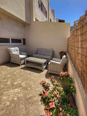 A patio area with wicker furniture, a tiled floor, and a bamboo fence. - Los Corales 1 - Four Bed Townhouse (Arona)