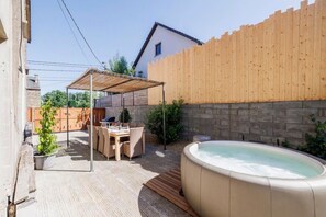 A backyard with a hot tub, a covered patio area, and a brick wall. - Le Gribou d'Ardennes a cottage for 9 people with jacuzzi, billiards and pétanque (Herbeumont)