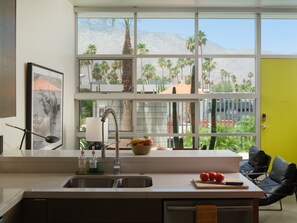 Eine moderne Küche mit einem großen Fenster, einer Spüle und einer Arbeitsplatte mit verschiedenen Gegenständen.