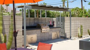 Ett utomhusområde med grillplats, sittplatser och en pergola.