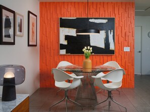 Un espace repas moderne avec une table ronde, des chaises blanches et un vase de fleurs.