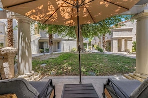 A courtyard with a pergola, stone columns, and a seating area with a view of the building's facade. - Welcome to Mesquite Breeze, Your Relaxing Palm Springs Getaway (Palm Springs)