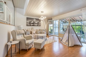 A spacious living area with a large sofa, a small round table, and a tent-like structure. - Holiday Home 'Joanna' with Mountain View, Private Terrace and Wi-Fi (Hennef)