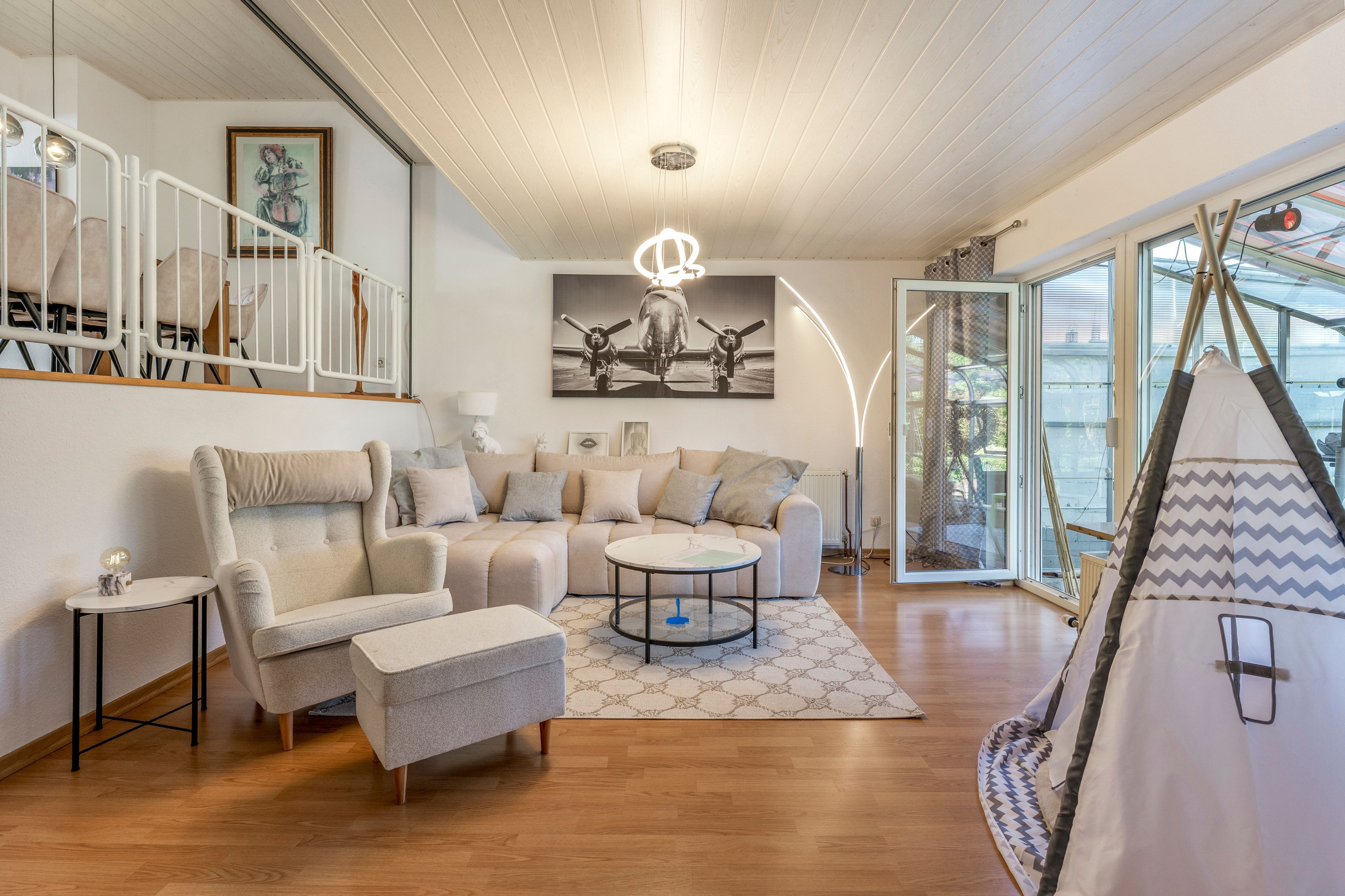 A modern living room with a sofa, armchairs, a coffee table, and a tent-like structure.
