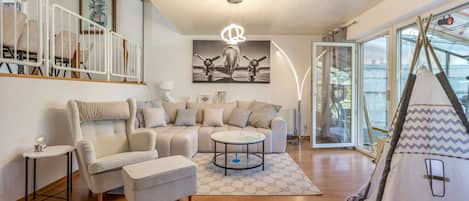 A modern living room with a sofa, armchairs, a coffee table, and a tent-like structure.