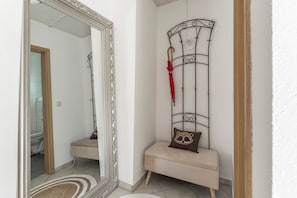A hallway with a large mirror, a bench, and a metal rack with an umbrella. - Holiday Home 'Joanna' with Mountain View, Private Terrace and Wi-Fi (Hennef)