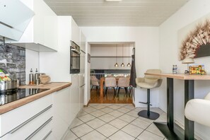A modern kitchen with a built-in oven and a dining area with a wooden table and chairs.