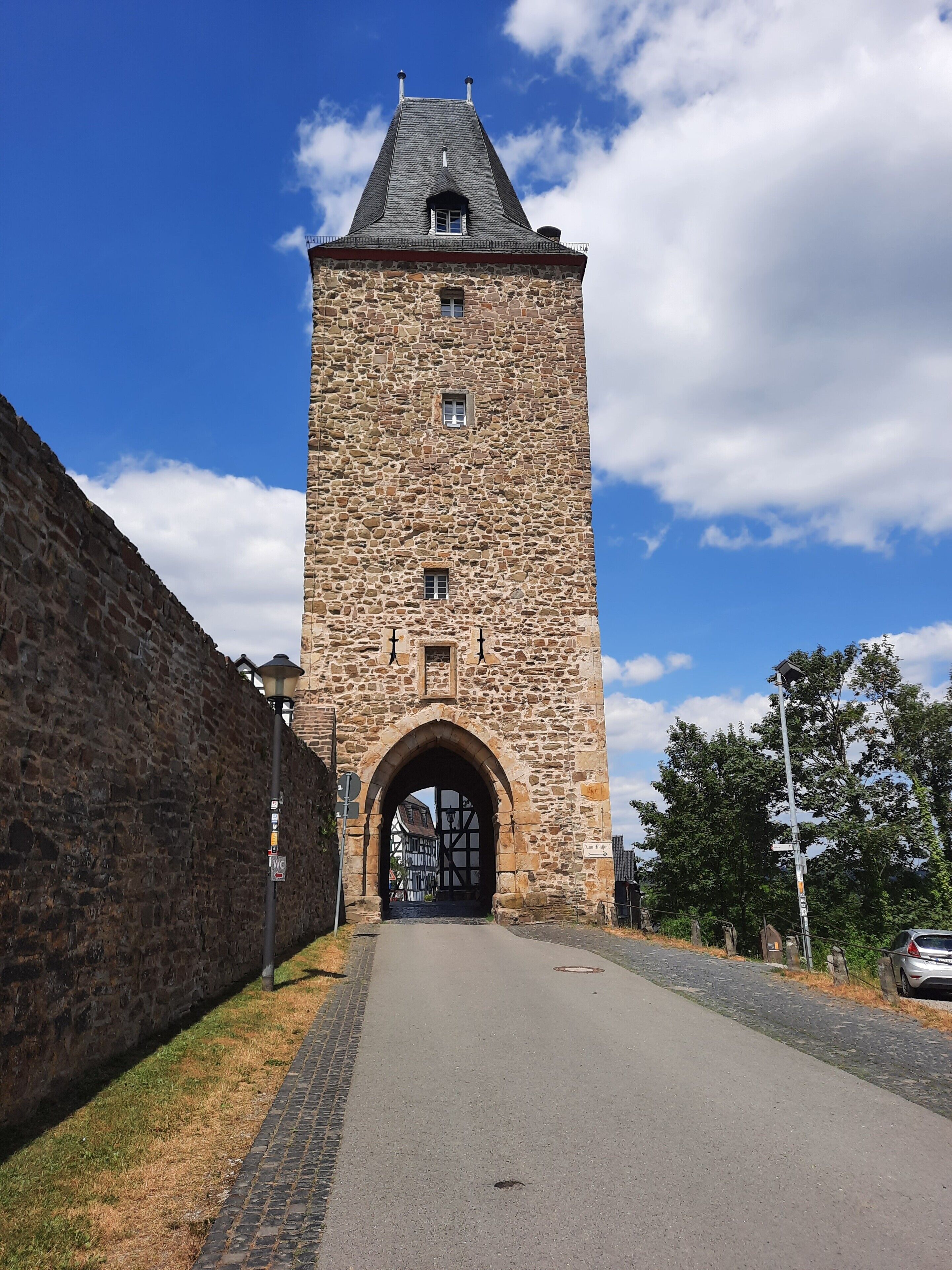 Une tour de pierre dotée d’une grande entrée en arc de cercle, un chemin pavé et un ciel dégagé.